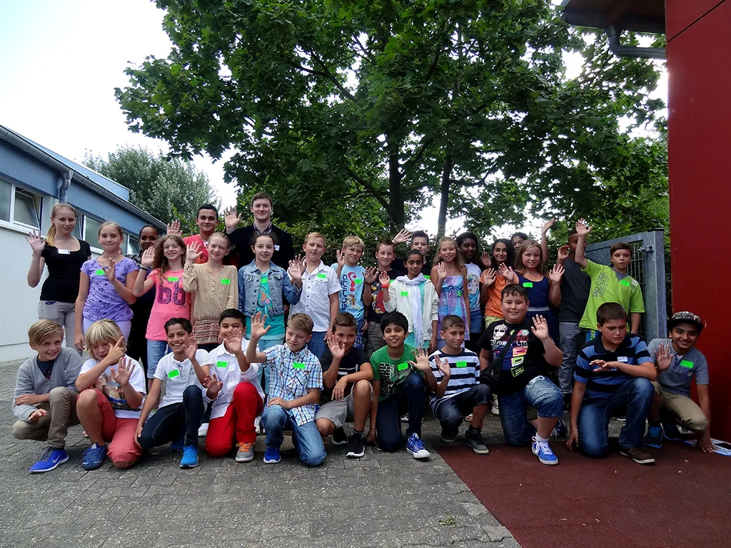 Klassenfoto einer neuen fünften Klasse, viele Kinder winken in die Kamera.
